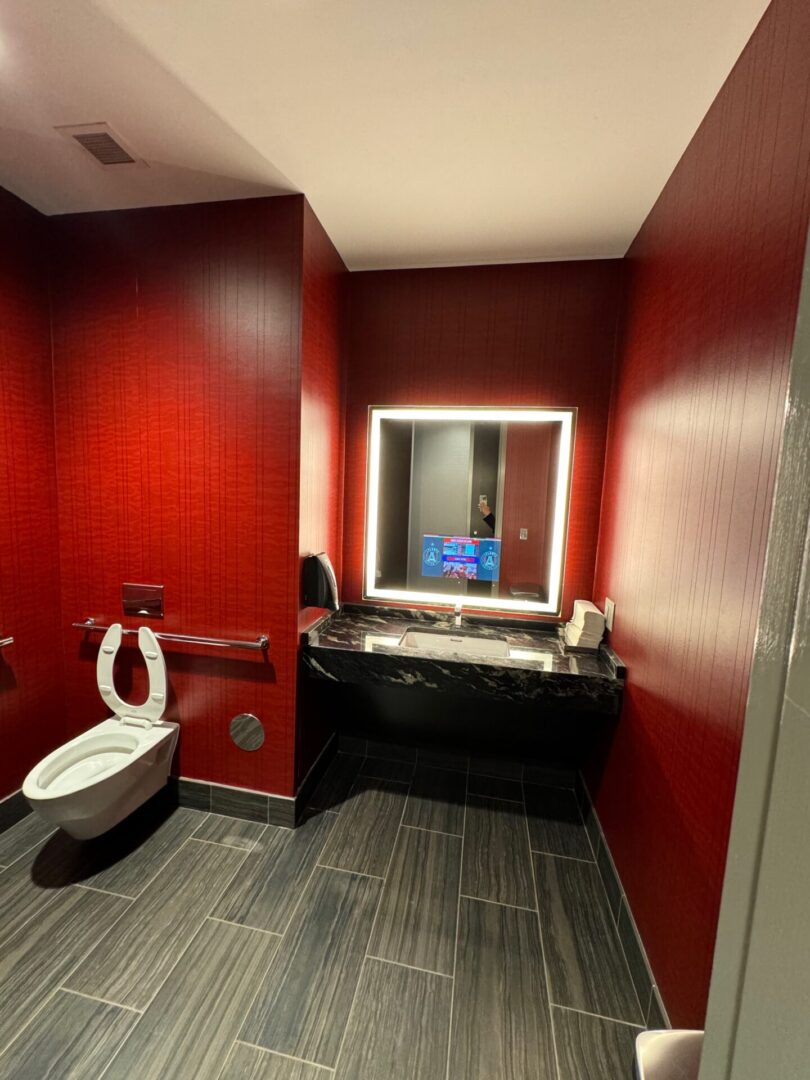 A bathroom with red walls and black trim.